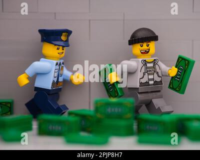 Tambov, Russische Föderation - 25. März 2023 Ein Lego-Dieb mit Geld, das vor einer Lego-Polizeibeamten-Minifigure davonläuft Stockfoto