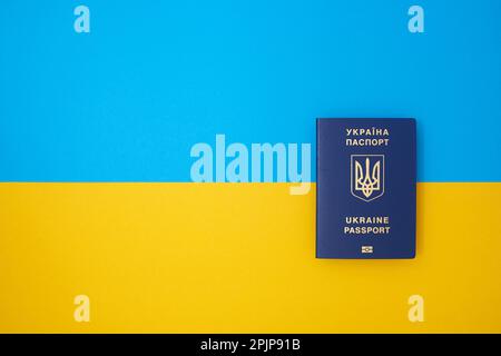 Ein blauer ukrainischer biometrischer Reisepass auf der ukrainischen Nationalflagge in der Draufsicht Stockfoto