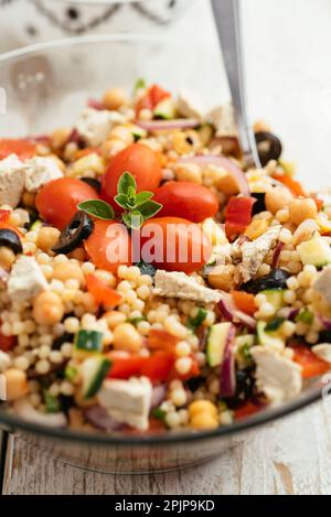 Hausgemachter mediterraner Couscous-Salat mit Paprika, Zucchini, Tomaten, Kichererbsen, olivem und veganem Feta. Stockfoto