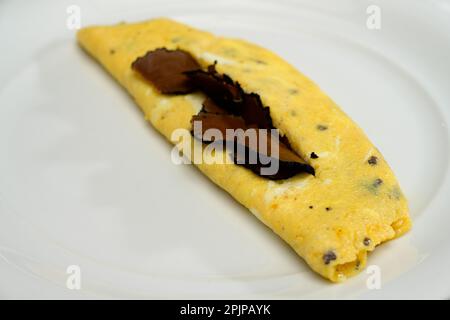 Französische Trüffel-Omelette-Eier oder Omelette-Auc-Trüffel mit schwarzen Sommertrüffeln auf einem weißen Teller Stockfoto