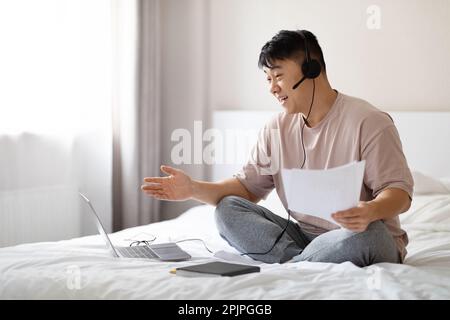 Freundlicher asiatischer Geschäftsberater, der von zu Hause aus arbeitet, Schlafzimmer-Inneneinrichtung Stockfoto