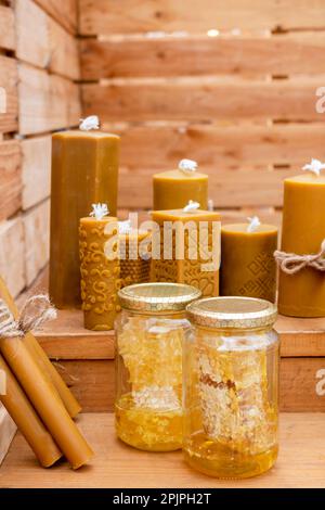 Honigwaben in Gläsern und Kerzen mit verschiedenen Mustern, handgefertigt mit Bienenwachs auf Holz Stockfoto