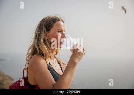 Eine Wanderer trinkt Wasser während einer Wanderung, Konzept der Hydratation und Gesundheit. Stockfoto