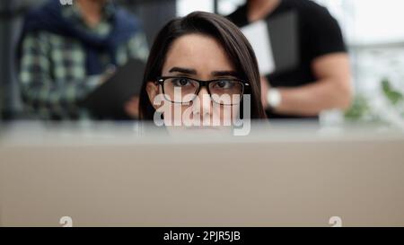 Selbstbewusste Geschäftsfrau, die lässige Kleidung trägt, während sie im Büro sitzt und arbeitet Stockfoto