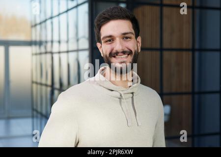 Lächelnder junger Geschäftsmann in einer Pullover-Pose. Geschäftskonzept „Karrierevermögen“ erreichen. Stockfoto