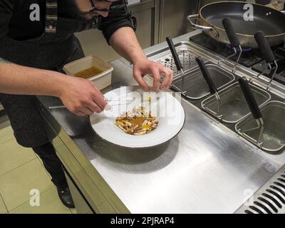 Koch-Pfannen gekochte Flambe atlantischer Tintenfisch mit Kartoffelsauce Creme Reduktion, Rettich, karamellisierte Zitrone und aromatische Kräuter, Gourmet-Trend Stockfoto