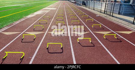 Vier Reihen gelber 6-Zoll-Minihürden, die in Fahrspuren auf einer Piste aufgestellt sind, damit Läufer beim Wicket-Bohrer überfahren werden können. Stockfoto