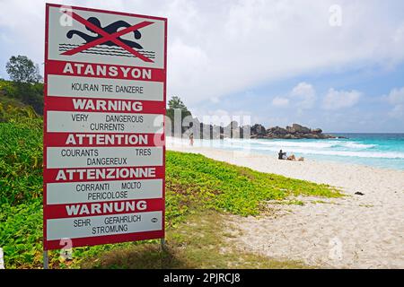 Schild mit Warnungen in verschiedenen Sprachen über Strömungen, Grand Anse Traumstrand, La Digue Island, Seychellen Stockfoto