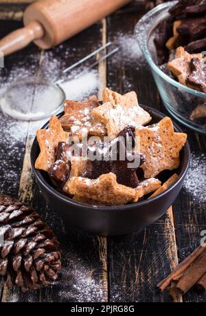 Sortierte weihnachten Ingwer Cookies auf Platte mit Zimtstangen, kiefernzapfen über dunklen Holztisch. 6 Stern cookies Stockfoto