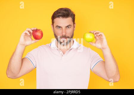 Ein Mann, der leckeren Apfel bastelt. Mann isst Apfel, Studioporträt. Frühstück am Morgen. Mann mit gesunden Zähnen, der Äpfel auf gelb isoliertem Hintergrund hält. Ma Stockfoto