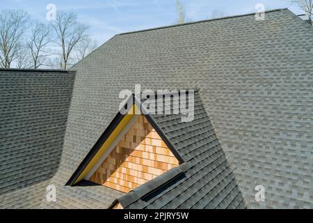 Bei der Montage der oberen Abdeckung von Asphaltschindeln auf neuen Hausqualitätsdächern werden Dacharbeiten überprüft Stockfoto