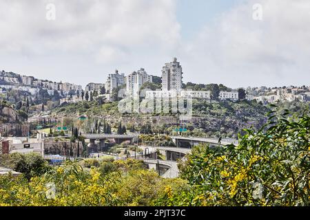 Straßenkreuzung in Haifa City und Stadthäuser im Frühling im Grünen Stockfoto