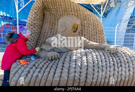 PRODUKTION - 03. April 2023, Mecklenburg-Vorpommern, Warnemünde: Sandkünstler Andrius Petkus aus Litauen arbeitet mit einem Taucher an einer großen Sandskulptur. Sechs Künstler aus fünf Ländern kreieren die Figuren für die 13. Sand World aus 300 Tonnen Spezialsand direkt am Meereskanal in Warnemünde. Unter dem Motto „Metamorphose - Blown by the (Baltic) Wind“ werden bis zum 06. April 2023 verschiedene Motive rund um das Thema Meer geschaffen. Die Show wird bis zum 29. Oktober 2023 ausgestellt. Foto: Jens Büttner/dpa Stockfoto