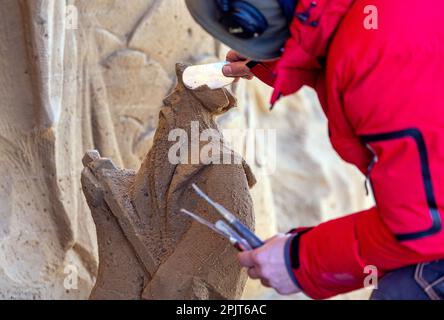 PRODUKTION - 03. April 2023, Mecklenburg-Vorpommern, Warnemünde: Ein Künstler aus Lettland arbeitet an einer großen Sandskulptur mit Neptun und anderen Unterwasserkreaturen. Sechs Künstler aus fünf Ländern kreieren die Figuren für die 13. Sand World aus 300 Tonnen Spezialsand direkt am Meereskanal in Warnemünde. Unter dem Motto „Metamorphose - Blown by the (Baltic) Wind“ werden bis zum 06. April 2023 verschiedene Motive rund um das Thema Meer geschaffen. Die Show wird bis zum 29. Oktober 2023 ausgestellt. Foto: Jens Büttner/dpa Stockfoto