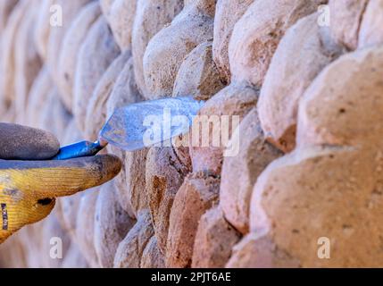 PRODUKTION - 03. April 2023, Mecklenburg-Vorpommern, Warnemünde: Ein Künstler aus Litauen arbeitet an einer großen Sandskulptur mit einem Spachtel. Sechs Künstler aus fünf Ländern kreieren die Figuren für die 13. Sand World aus 300 Tonnen Spezialsand direkt am Meereskanal in Warnemünde. Unter dem Motto „Metamorphose - Blown by the (Baltic) Wind“ werden bis zum 06. April 2023 verschiedene Motive rund um das Thema Meer geschaffen. Die Show wird bis zum 29. Oktober 2023 ausgestellt. Foto: Jens Büttner/dpa Stockfoto