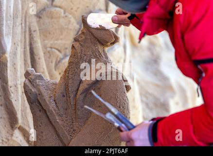 PRODUKTION - 03. April 2023, Mecklenburg-Vorpommern, Warnemünde: Ein Künstler aus Lettland arbeitet an einer großen Sandskulptur mit Neptun und anderen Unterwasserkreaturen. Sechs Künstler aus fünf Ländern kreieren die Figuren für die 13. Sand World aus 300 Tonnen Spezialsand direkt am Meereskanal in Warnemünde. Unter dem Motto „Metamorphose - Blown by the (Baltic) Wind“ werden bis zum 06. April 2023 verschiedene Motive rund um das Thema Meer geschaffen. Die Show wird bis zum 29. Oktober 2023 ausgestellt. Foto: Jens Büttner/dpa Stockfoto