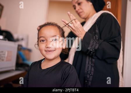 Lehrtraditionen. Eine Mutter, die ihrer Tochter half, ein Kopftuch anzuziehen. Stockfoto