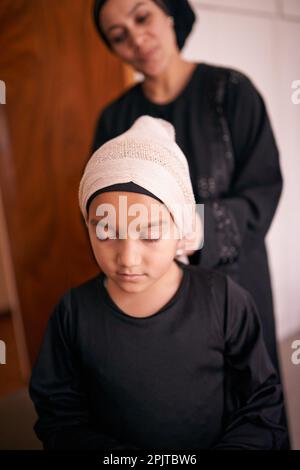 Die Tradition weitergeben. Eine Mutter, die ihrer Tochter half, ein Kopftuch anzuziehen. Stockfoto