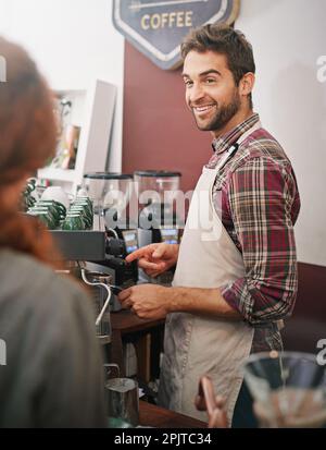 Kommt sofort. Ein junger männlicher Barista, der einen Gast bedient. Stockfoto