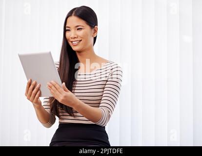 Ich überprüfe ihre Tagesplanung. Eine junge asiatische Geschäftsfrau, die ein digitales Tablet im Büro benutzt. Stockfoto
