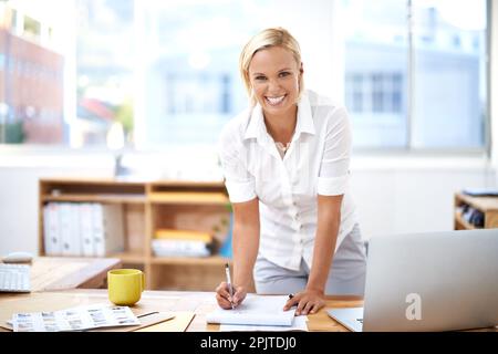 Das Geschäft boomt. Porträt einer attraktiven jungen Geschäftsfrau, die Papiere unterschreibt. Stockfoto