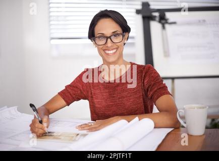 Diese Pläne kommen gut voran. Eine attraktive junge Architektin, die in ihrem Büro arbeitet. Stockfoto