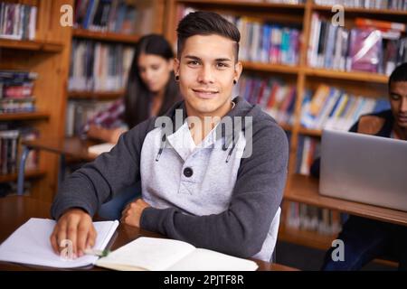 Hes ein so fleißiger Student. Beschnittenes Porträt eines hübschen jungen Studenten, der fleißig in seinem Klassenzimmer arbeitet. Stockfoto