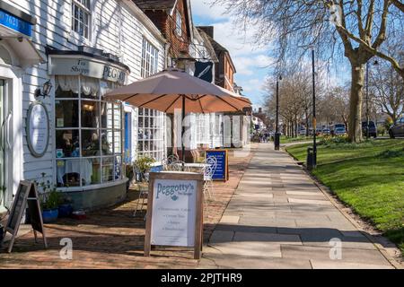 Geschäfte und Cafés auf dem breiten Bürgersteig in der Tenterden High Street, Kent, Großbritannien Stockfoto