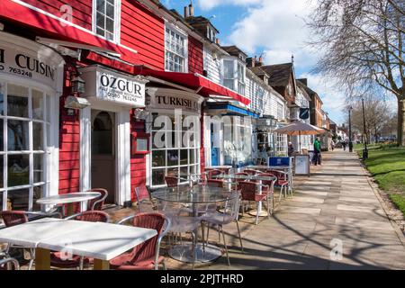 Geschäfte und Cafés auf dem breiten Bürgersteig in der Tenterden High Street, Kent, Großbritannien Stockfoto