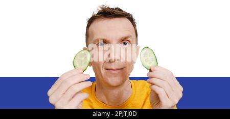 Ein Mann mittleren Alters hält zwei Gurkenscheiben in den Händen Stockfoto