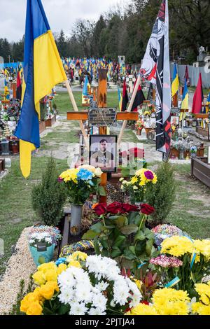 1. April 2023, Lemberg, Ukraine: Das Grab eines gefallenen Soldaten mit einem Porträt auf dem Ehrenfeld auf dem Friedhof in Lemberg. Yurii Ruf war Schriftsteller, öffentliche Figur, Patriot der Ukraine und eine bekannte Person in Lemberg und der Ukraine. Er organisierte viele Veranstaltungen, ein Festival usw. Als der Krieg begann, ging er als Freiwilliger an die Front und wurde bei einer Kampfmission in der Region Luhansk am 1. April 2022 getötet. Das Ereignis auf den Fotos ist das Gedenken an Jurij in der Kirche und auf dem Feld der ehrenvollen Beerdigungen auf dem Friedhof Lychakivskyi in Lemberg am ersten Jahrestag seines Todes. Relat Stockfoto