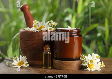 Ein Glas Handcreme, Kamille und Kosmetikartikel auf einem Holztisch Stockfoto