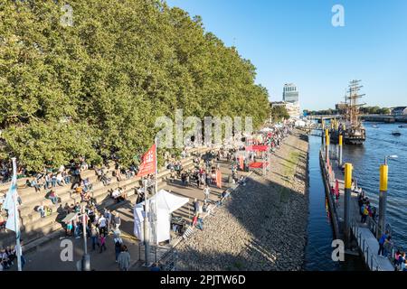 Menschen am Martime Day, Maritime Woche in Cafés und Bars am Schlachte die historische Uferpromenade am Weser mit Booten und Großseglern. Bremen. Stockfoto