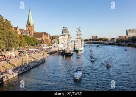 Menschen am Maritime Day, in Cafés, Bars an der historischen Wasserpromenade Schlachte am Weser mit Booten, Großseglern und der St. Martin's Church, Bremen. Stockfoto