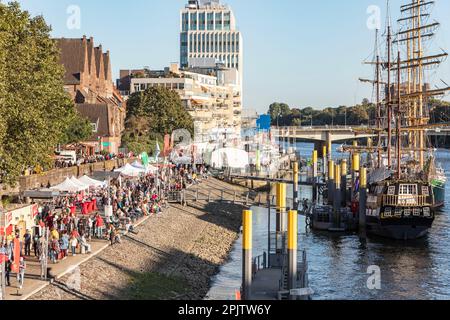 People at Maritime Day - Maritime Woche in Cafés und Bars an der historischen Uferpromenade Schlachte am Weser mit Booten und Großseglern, Bremen. Stockfoto