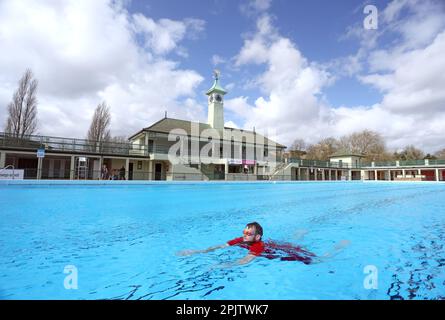 Peterborough, Großbritannien. 30. März 2023. Der diensthabende Manager Mason Matchwick genießt ein Bad im Peterborough Lido, der sich auf die Eröffnung der Sommersaison am 1. April in Peterborough, Cambridgeshire, Großbritannien, vorbereitet. Die Peterborough Cathedral ist nur wenige hundert Meter vom Peterborough Lido entfernt, der 1936 erbaut wurde, und der Außenpool hat noch heute den fabelhaften Art-Deco-Look. Kredit: Paul Marriott/Alamy Live News Stockfoto