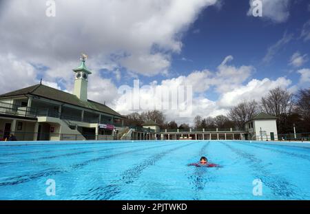 Peterborough, Großbritannien. 30. März 2023. Der diensthabende Manager Mason Matchwick genießt ein Bad im Peterborough Lido, der sich auf die Eröffnung der Sommersaison am 1. April in Peterborough, Cambridgeshire, Großbritannien, vorbereitet. Die Peterborough Cathedral ist nur wenige hundert Meter vom Peterborough Lido entfernt, der 1936 erbaut wurde, und der Außenpool hat noch heute den fabelhaften Art-Deco-Look. Kredit: Paul Marriott/Alamy Live News Stockfoto