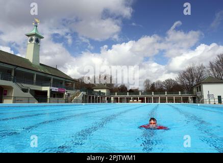 Peterborough, Großbritannien. 30. März 2023. Der diensthabende Manager Mason Matchwick genießt ein Bad im Peterborough Lido, der sich auf die Eröffnung der Sommersaison am 1. April in Peterborough, Cambridgeshire, Großbritannien, vorbereitet. Die Peterborough Cathedral ist nur wenige hundert Meter vom Peterborough Lido entfernt, der 1936 erbaut wurde, und der Außenpool hat noch heute den fabelhaften Art-Deco-Look. Kredit: Paul Marriott/Alamy Live News Stockfoto