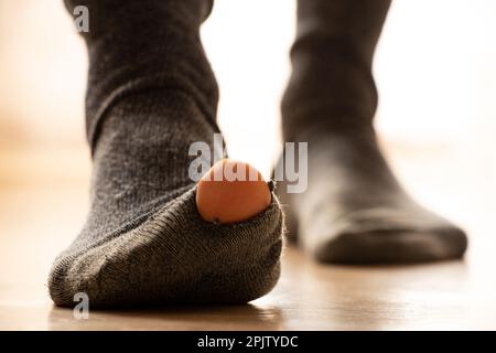 Frauenfüße in heiligen Socken stehen auf dem Boden des Hauses, Armut, Füße Stockfoto