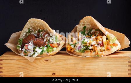 Fast Food im arabischen Stil, Pita-Brot gefüllt mit Falafel oder Hühnerfleisch mit Gemüsesalat und weißer Sauce auf dem Karlin Street Food Markt in Prag. Stockfoto