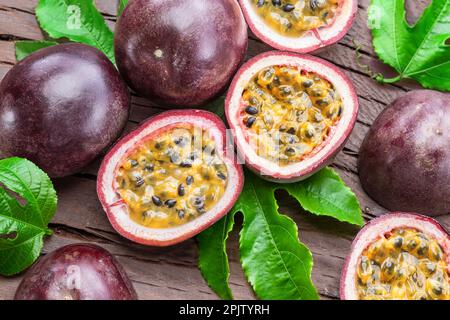 Dunkellila Passionsfrüchte und die Hälfte mit scheinbar Innenausstattung auf einem Holztisch. Stockfoto