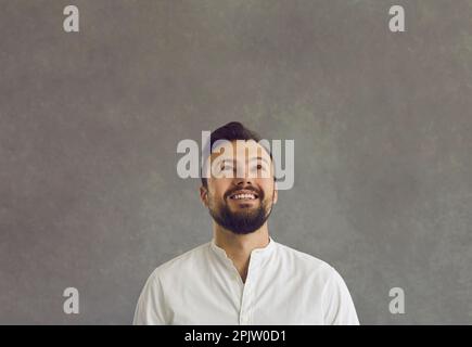 Porträt eines fröhlichen, lächelnden, jungen weißen Mannes, der aufblickt Stockfoto