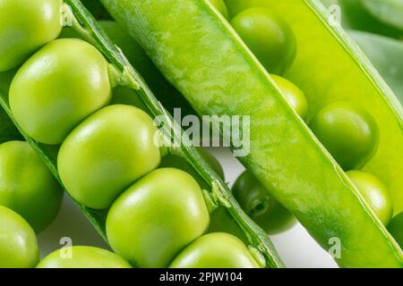 Reihen von perfekten grünen Erbsen in Hülsen Nahaufnahme. Stockfoto