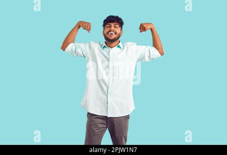 Porträt eines fröhlichen jungen Indianers in einem Hemd, der seine Arme beugt und lächelt Stockfoto