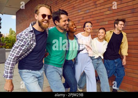 Fröhliche, sorgenfreie Gruppe von Freunden in lässiger Kleidung gehen gerne die Straße hinunter. Stockfoto