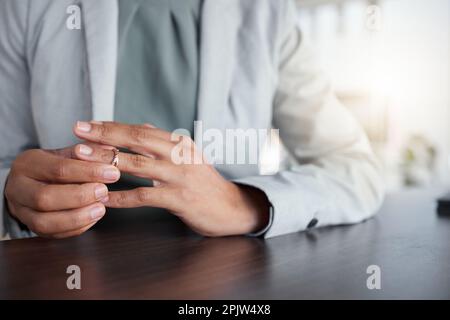 Hand oder Finger, Ring und Scheidung einer Frau am Tisch mit Zweifeln, Angst oder Gedanken an Depressionen. Weibliche Person, die Hochzeitsband-Schmuck abnimmt Stockfoto