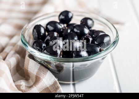 Entsteinte schwarze Oliven in der Schüssel auf dem Küchentisch. Stockfoto