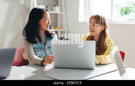 In einem Klassenzimmer mit Programmieren interagieren zwei Mädchen miteinander, während sie lernen, auf einem Laptop zu programmieren. Studentinnen erhalten ein starkes Fundament in Prog Stockfoto