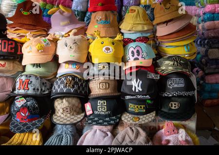 Gefälschte und gefälschte Designer-Kappen und -Hüte zum Verkauf auf dem Zentralmarkt in Pleiku, Vietnam. Stockfoto