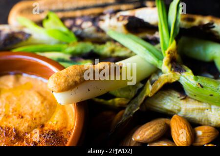 Kalk mit Romesco-Sauce. Kalk ist eine Vielfalt zarter Zwiebeln, die zwischen November und April wachsen. Stockfoto